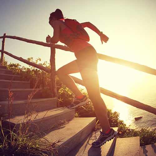 Active woman running up a running path of stairs